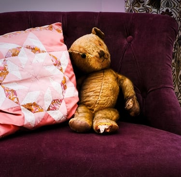 Teddy bear and patchwork cushion on purple velvet chair