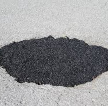 Fresh asphalt patch filling a pothole on a grey pavement road for driveway repair.