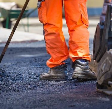 Asphalt contractor leveling and compacting new pavement on commercial parking lot in San Antonio