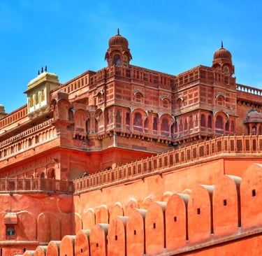 Intricate red sandstone architecture of Junagarh Fort in Bikaner, Rajasthan under a clear blue sky.