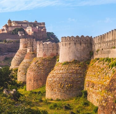 The massive fortified stone walls of Kumbhalgarh Fort in Rajasthan, India, under a blue sky.