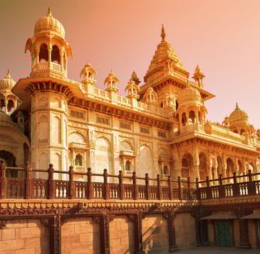 The Jaswant Thada white marble cenotaph in Jodhpur, India, glowing at sunset with birds flying by.