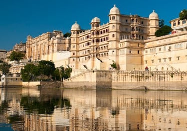 The majestic City Palace Udaipur reflecting in the calm waters of Lake Pichola in Rajasthan, India.