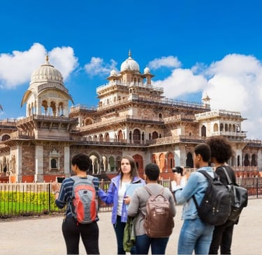 Tourists with backpacks taking photos of the historic Albert Hall Museum in Jaipur, India.