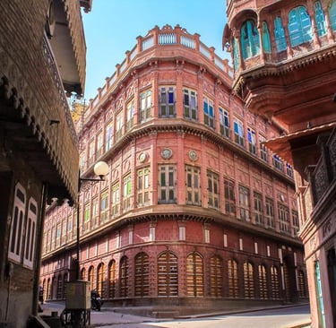 Historic pink sandstone haveli with intricate windows and traditional Rajasthani architecture in Bikaner, India.