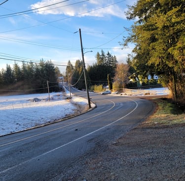 a curved country road with a snowy field on one side