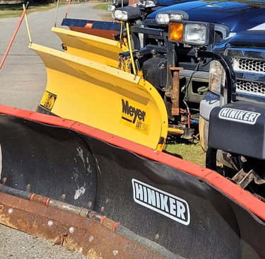 a picture of 4 plow blades attached to trucks includung the brands hiniker and meyer