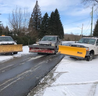 3 trucks with snow plows on the front parked