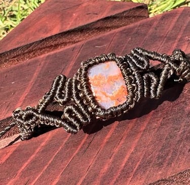 Pulsera de macramé artesanal con ágata naranja natural y tejido detallado en cordón marrón oscuro.
