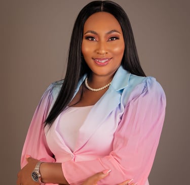 Professional portrait of a smiling woman wearing a pink and blue ombre blazer and pearl necklace.
