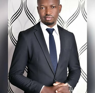 Professional portrait of a man wearing a black business suit and blue tie against a patterned background.