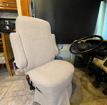 Light beige fabric upholstery on a swivel RV captain chair inside a motorhome cockpit.