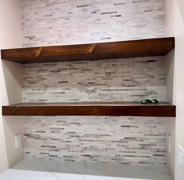 Rustic dark wood floating shelves mounted on a light grey stone mosaic tile backsplash.