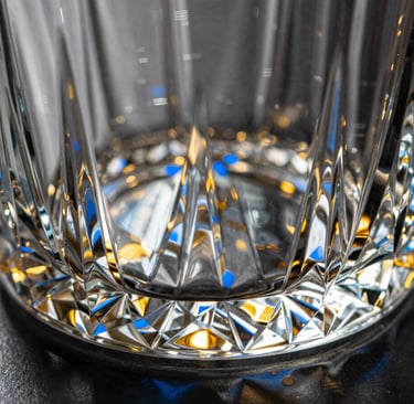 Macro detail shot of a heavy crystal decanter base with geometric cuts refracting golden light, azure blue shadows, 35mm