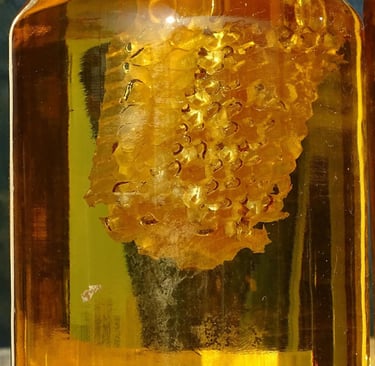 Raw organic honeycomb submerged in a glass jar of golden liquid honey.