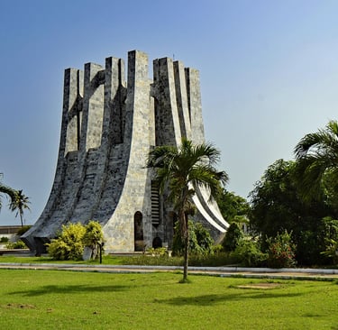The Kwame Nkrumah Memorial Park and Mausoleum in Accra, Ghana, with palm trees and green grass.