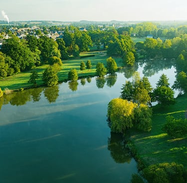 Vue aérienne d'un étang paisible traversant un parc verdoyant près d'un quartier résidentiel au l