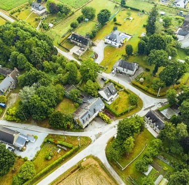 Vue aérienne d'un village rural Français avec des maisons en pierre, des jardins verdoyants et des r