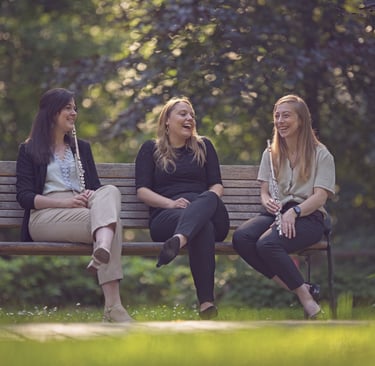 three women sitting on a bench in a park
