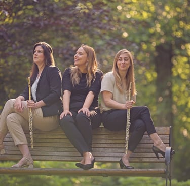 three women sitting on a bench in a park