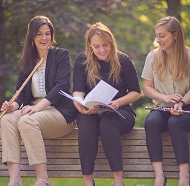 three women sitting on a bench in a park