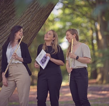 three women playing flute and flute in a wooded area