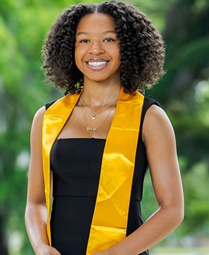 a woman in a black dress and yellow sasher belt