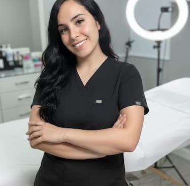 Esteticista profesional en uniforme negro posando en una moderna sala de tratamientos de cuidado de 