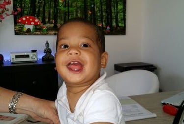 a baby boy smiling and holding a magazine