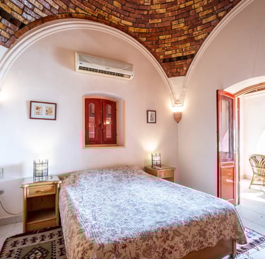 Rustic bedroom with a vaulted brick ceiling, arched walls, and traditional Mediterranean decor.