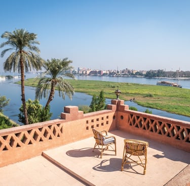 A scenic rooftop terrace overlooking the Nile River in Egypt with palm trees and cruise boats.