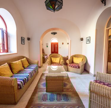 Traditional Middle Eastern living room featuring wicker furniture, colorful pillows, and arched doorways.