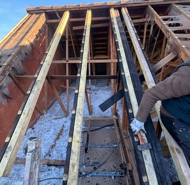 Artisan charpentier réalisant le renforcement et la rénovation d'une charpente en bois traditionnelle à Montmorency (95)