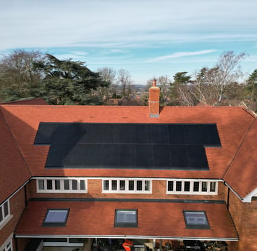 Aerial view of a residential brick house with black solar panels in Buckinghamshire