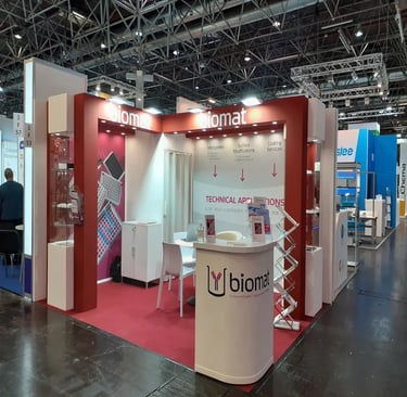 Bespoke red architectural exhibition pavilion for Biomat at Medica Düsseldorf featuring integrated glass showcases.