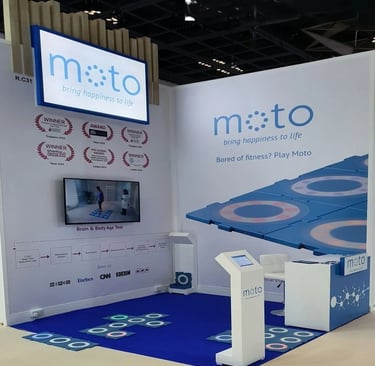 Custom interactive healthcare stand for Moto at Medica Dusseldorf with digital screens and branding by World Expo Pro.