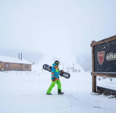 a man in a bright green jacket and green pants holding a snowboard chapelco argentina