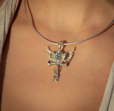 Pecho de una mujer con  un collar con un dije en plata y baño de oro