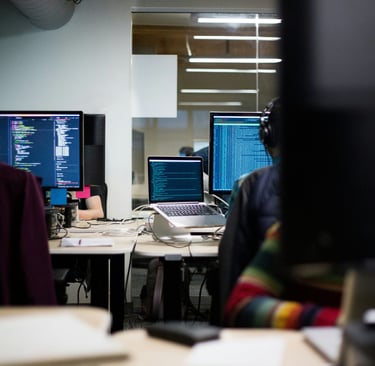 People at desks with code on monitors