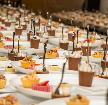 Elegant catered dessert assortment with chocolate mousse cups and fruit tarts on banquet plates.