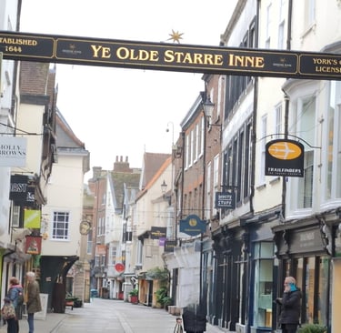 image of a ols street in York. has a sign across the road that has aname of a inn.