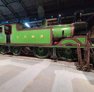 an old steam engine with LSWR painted on the side. Static  within an exhibtion at the NRM, York