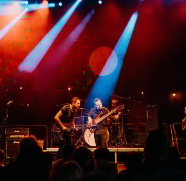 A lively band performing on stage with vibrant lighting in a night setting.