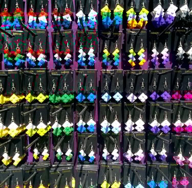 A vibrant display of handmade colorful LEGO earrings hanging on black retail display cards.