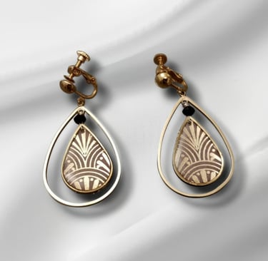 Vintage gold screw-back clip-on earrings with Art Deco teardrop patterns on white silk.
