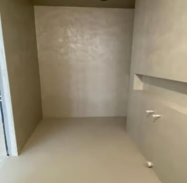 Beige microcement finish without joints on the walls and floor.