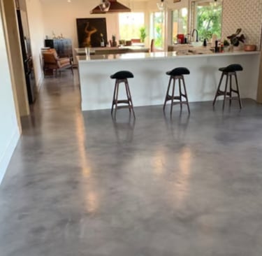 Modern open-plan kitchen with polished grey concrete flooring.