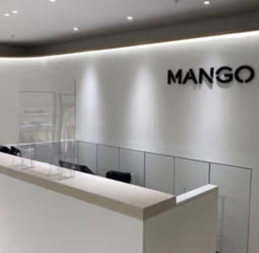 Minimalist Mango retail store interior featuring a white checkout counter and brand logo.