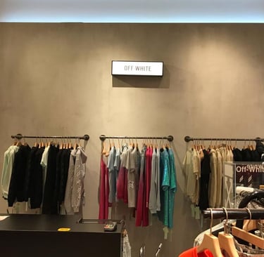 Off-White luxury streetwear clothing on hanging display racks in a modern boutique retail store.