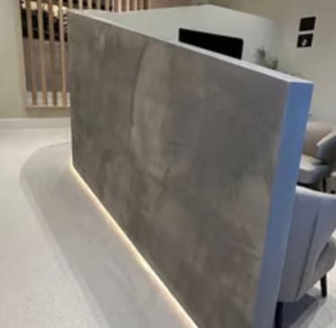 Modern waiting area with grey textured microcement partition with under-cabinet lighting and leather